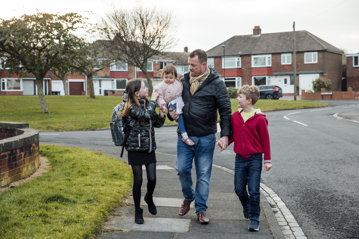 Father walking with three children in a neighbourhood