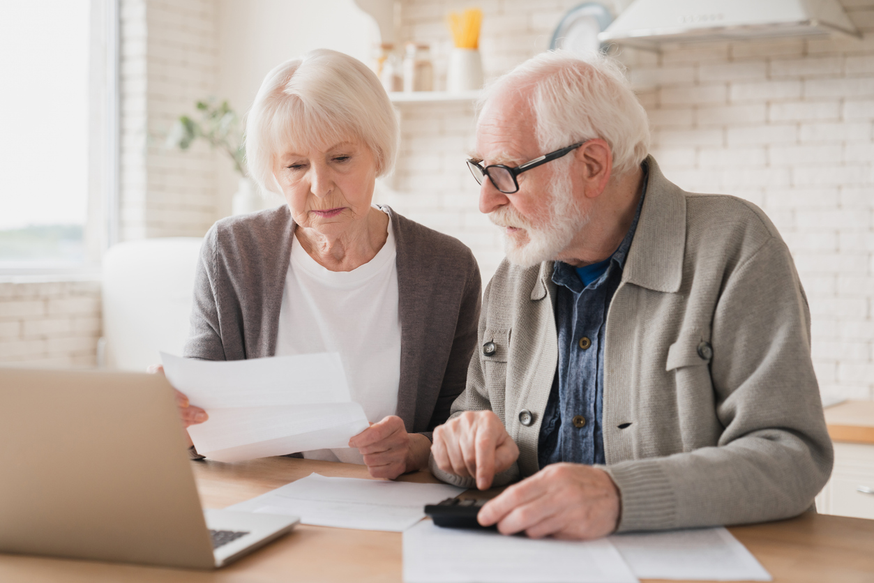 Couple using a calculator while reviewing insurance costs